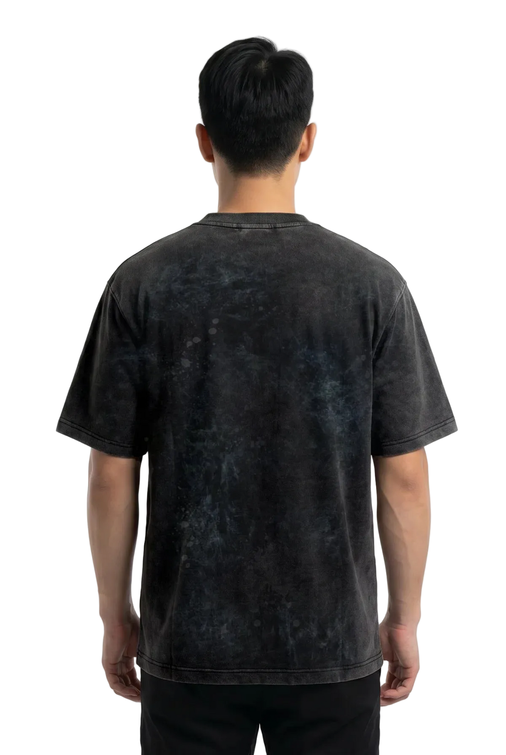 A man viewed from behind wearing a dark charcoal gray mineral-wash t-shirt and black pants, standing against a plain white studio background.