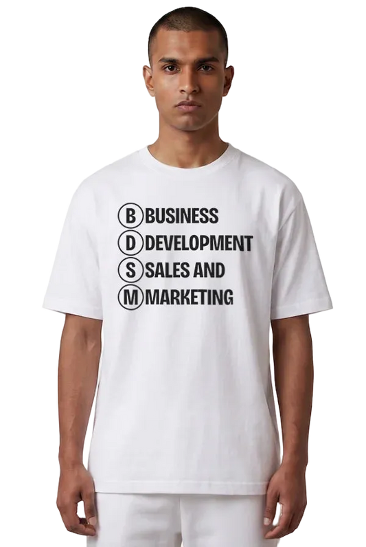 A man wearing a white short-sleeve t-shirt with black printed text reading 'BUSINESS DEVELOPMENT SALES AND MARKETING' inside circular letter boxes, paired with white pants, against a plain white background.