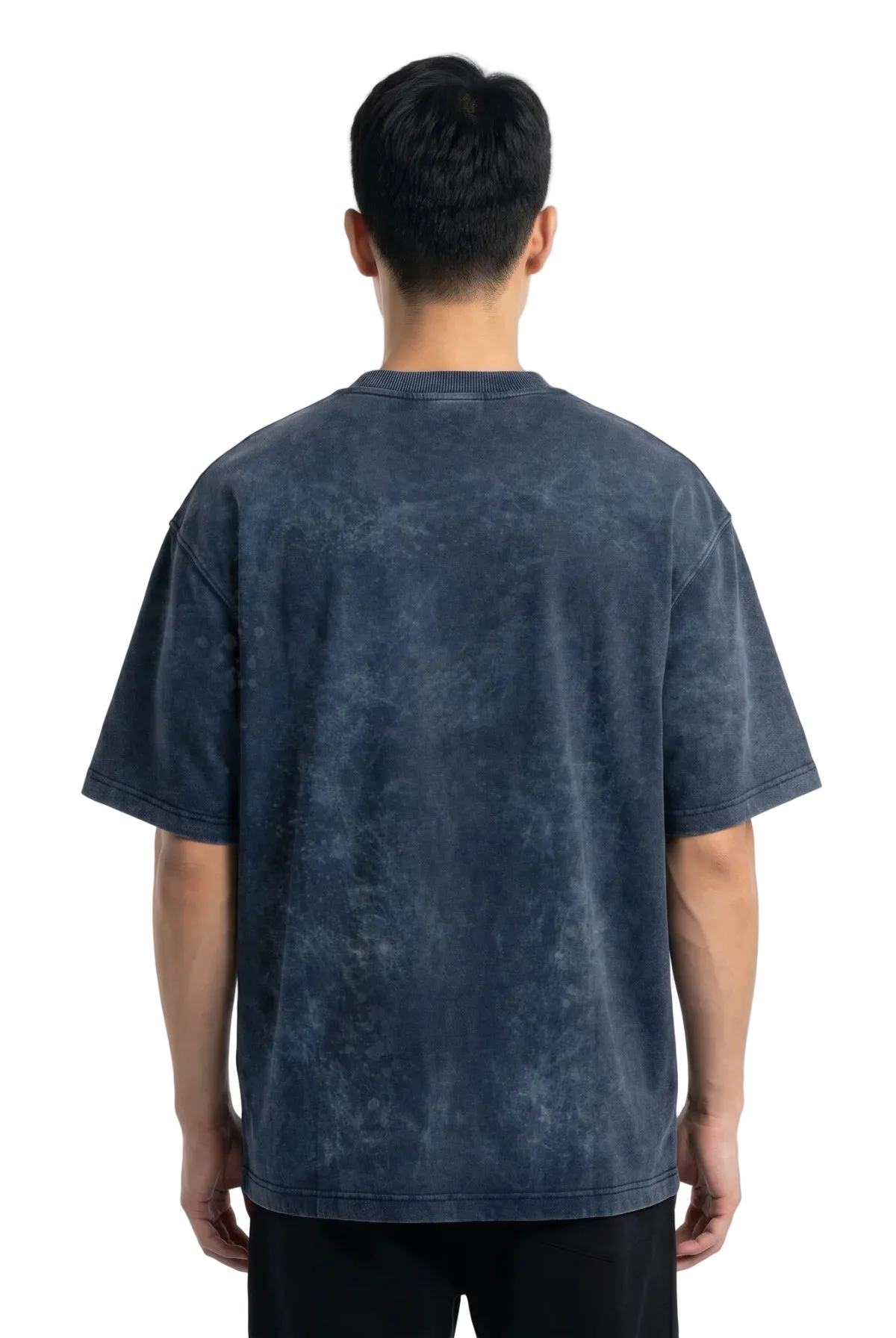 A man viewed from the back wearing an oversized short-sleeve t-shirt with a dark blue mineral-wash or acid-wash texture, paired with black pants against a white studio background.