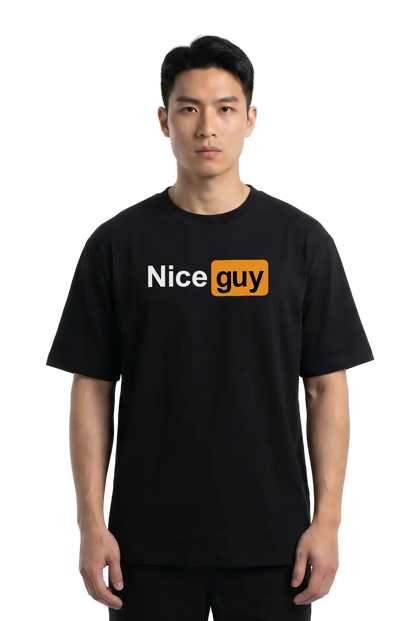 A man wearing a black short-sleeve t-shirt with a graphic on the chest that reads 'Nice guy' in white and orange, set against a plain white studio background.