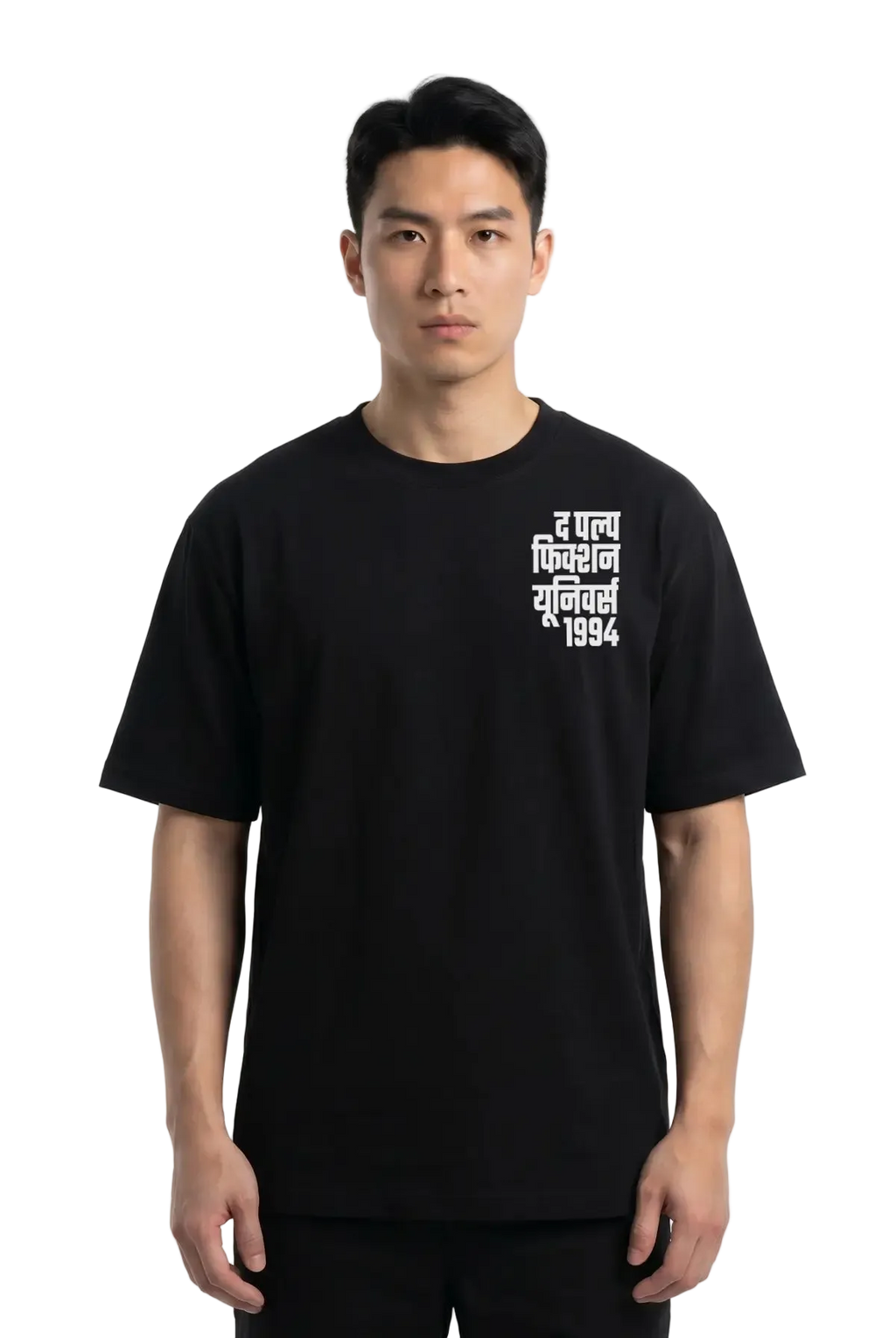 A man wearing a black short-sleeve t-shirt with white Devanagari text (the pulp Fiction Universe) on the left chest, photographed against a plain white studio background.