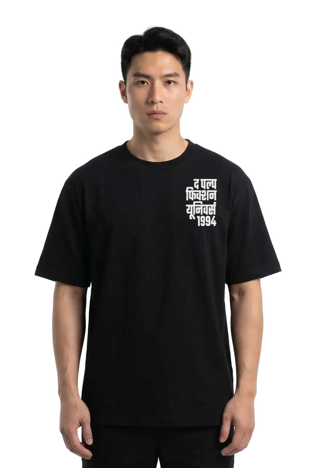 A man wearing a black short-sleeve t-shirt with white Devanagari text (the pulp Fiction Universe) on the left chest, photographed against a plain white studio background.