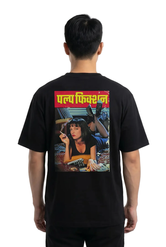A man viewed from the back wearing a black t-shirt with a large graphic print on the back. The print features the Hindi text 'Pulp Fiction' in yellow on a red banner above a colorful illustration of a woman.