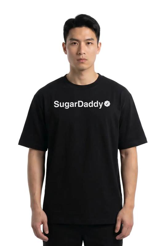 A man wearing a black short-sleeve t-shirt with 'Sugar Daddy' printed in white across the chest, photographed against a plain white studio background.